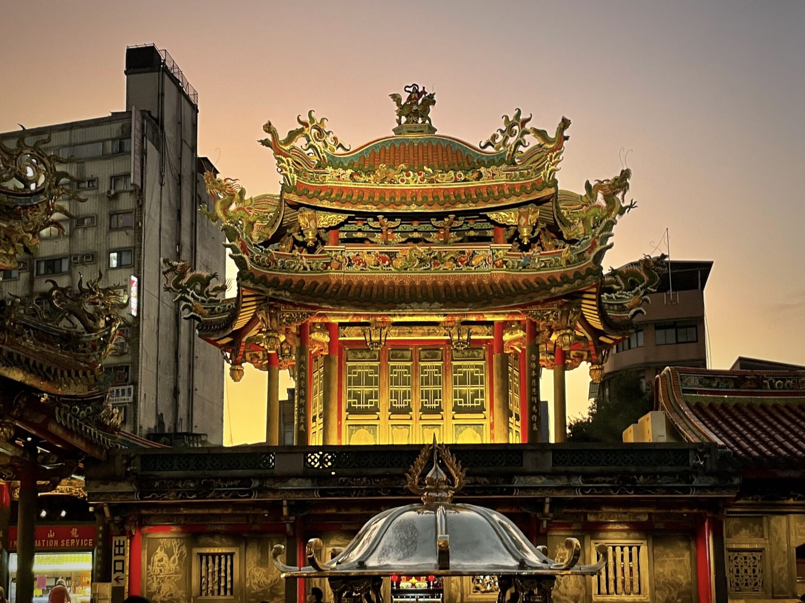 Image shows the vibrant Longshan Temple at sunset, highlighting the colors of gold and red.